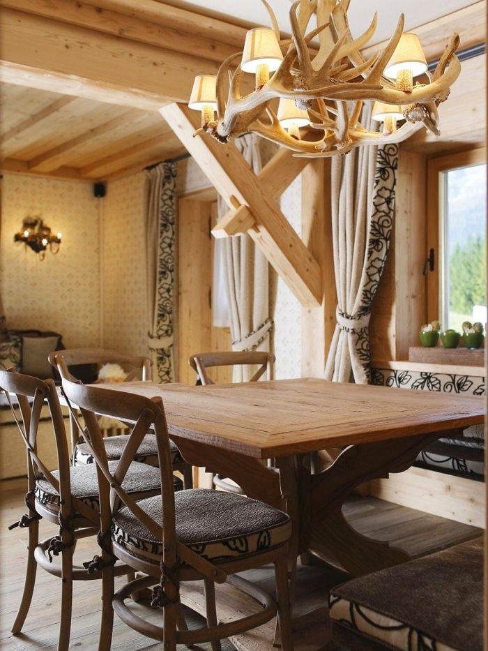 Wooden dining table and antler chandelier in an apartment in a rustic style