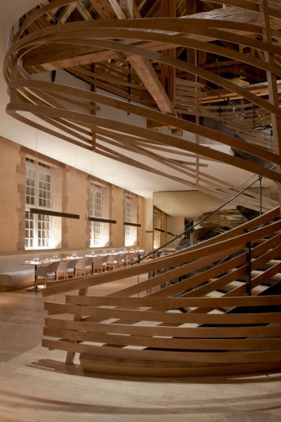 A view towards the curbed wooden staircase - trendy commercial interior design with wooden accents