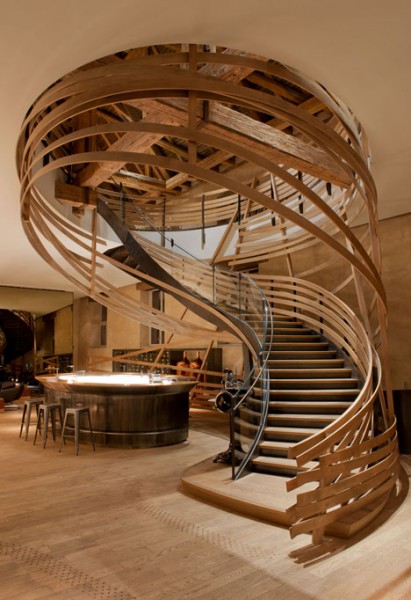 Attractive and creative curved staircase leads the visitors to the second level - trendy commercial interior design with wooden accents