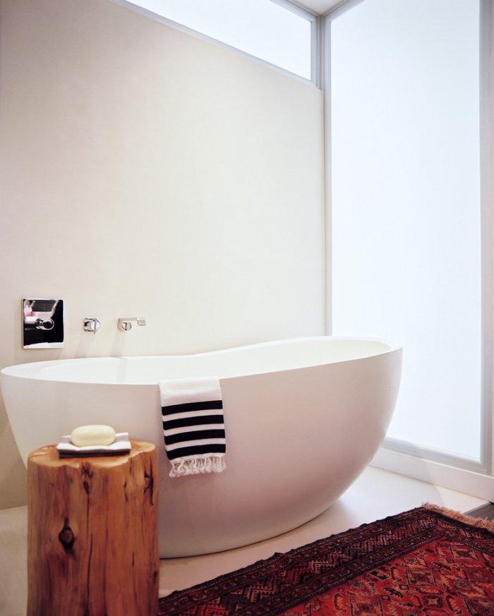 Chic bathroom with moderen bathtub, vintage rug and rustic stool