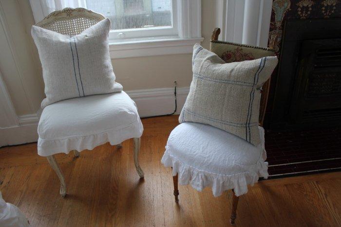 Farmhouse chic pillows decorate the two vintage chairs in the living room