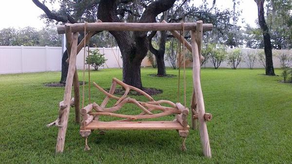 Garden swing made of barn beams and placed on the lawn