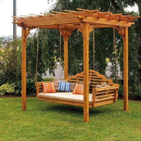 Garden swing under a small wooden pergola near trees