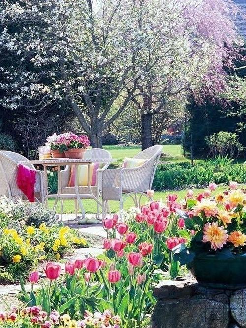 Outdoor dining set in a romantic garden with a lot of tulips and yellow flowers