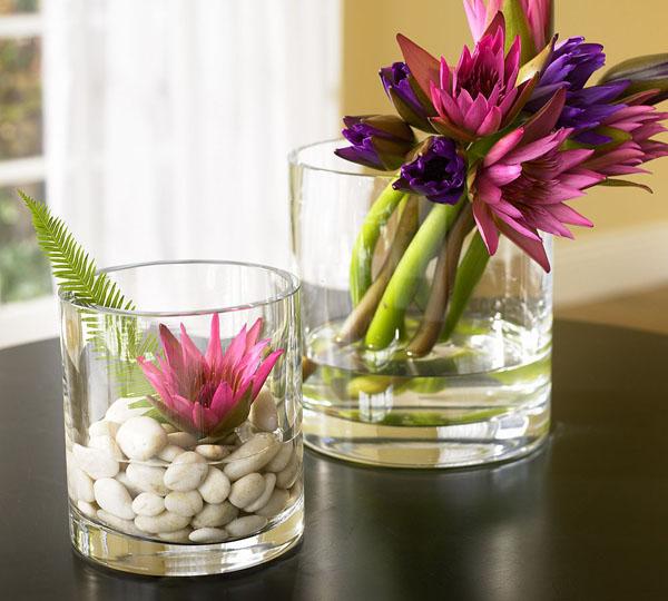 Beautiful decorative flowers placed inside whiskey glasses with water and pebbles