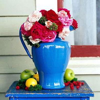 Colorful flowers inside a blue porcelain pitcher placed at the front porch