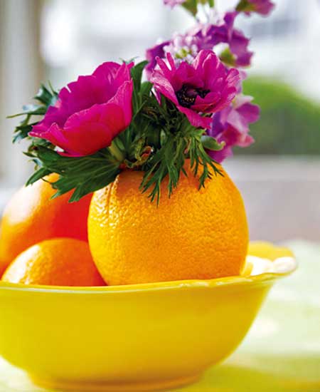 Flowers placed inside a hollowed orange that functions as a vase