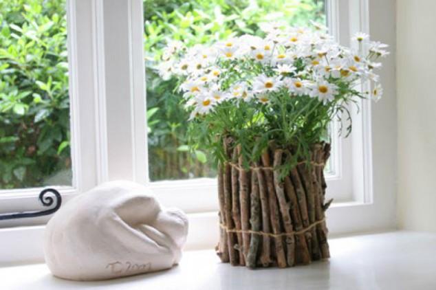 Fresh lawn flowers in a vesel made of natural branches wrapped together