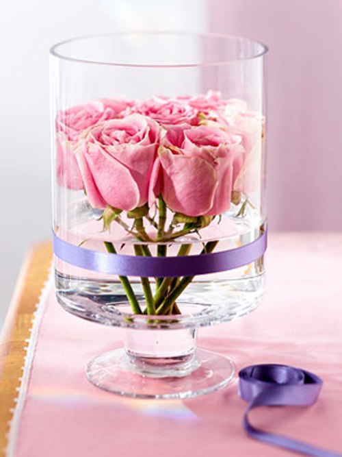 Gentle pink roses in an elegeant high glass ried with a silk ribbon