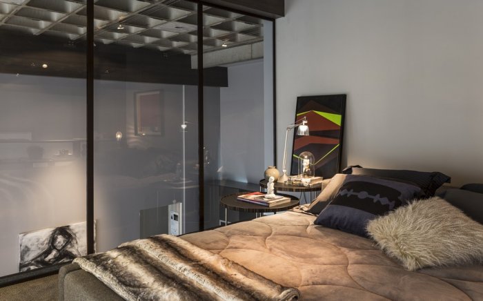 Modern loft bedroom with glass wall and abstract paiting as an accent in the interior