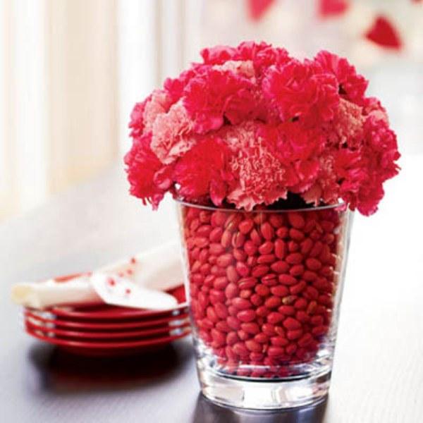 Red flowers and hip fruits inside a high glass used at the dinner table