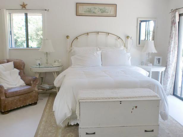 Shabby chic bedroom in white with comroftable bed and old armchair
