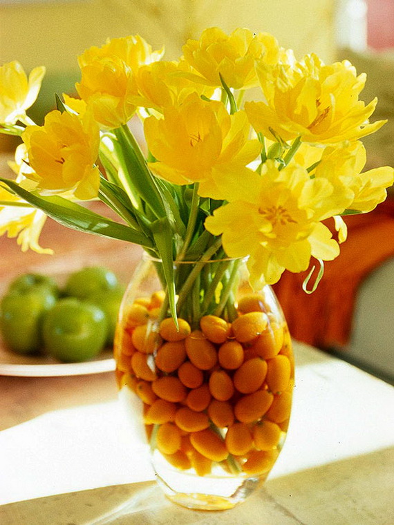 Yellow flowers inside a glass jar full of water and corn for decoration