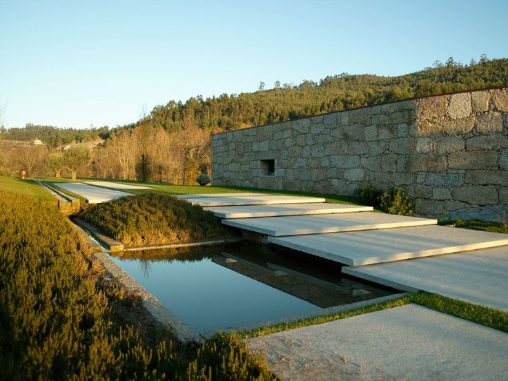 Giant concrete pavers half covereing a minimalist pond