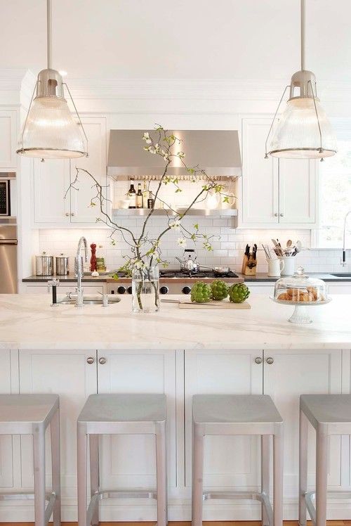 Huge white kitchen island with modern pendants above it