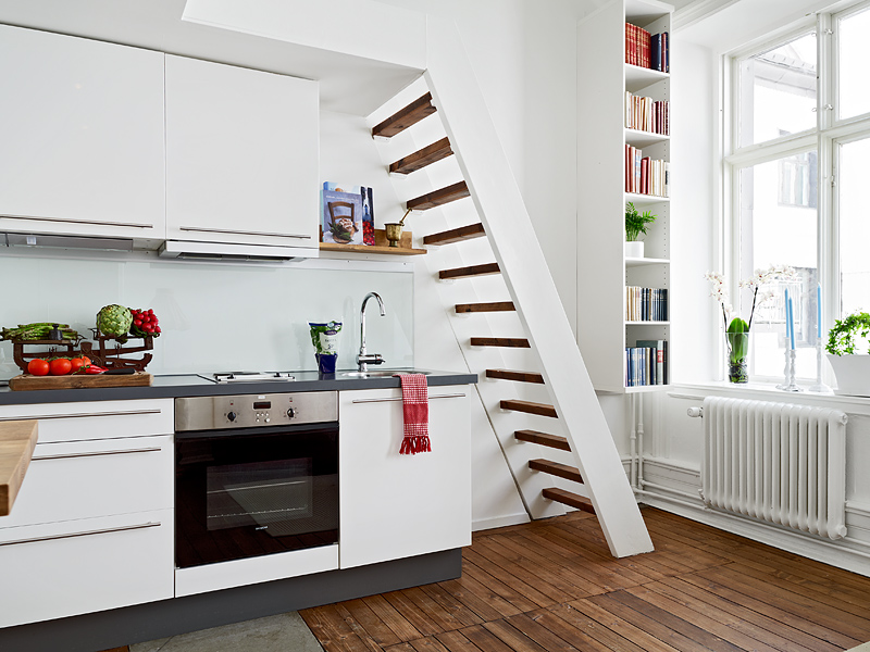 Small white kitchen - with stairs and bed above it