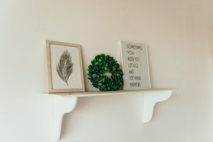 Two photos and a wreath on a picture shelf.