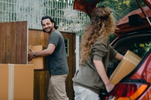 Free Cheerful modern male and female in comfortable casual clothes unpacking car trunk in green garden of new house while moving in together Stock Photo